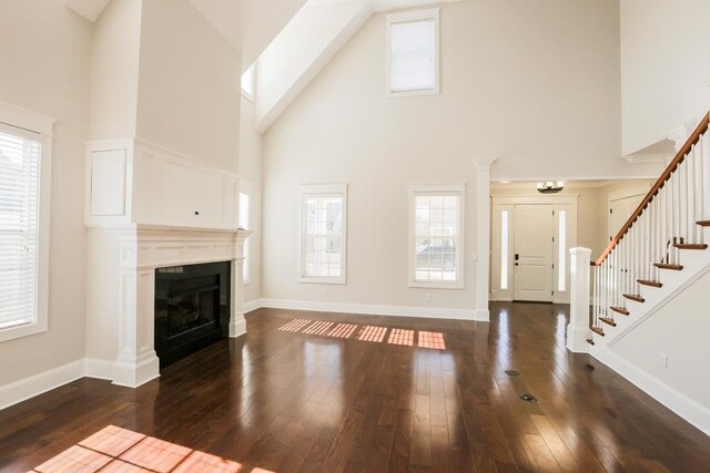 unfurnished living room featuring plenty of natural light, dark wood-type flooring, and high vaulted ceiling