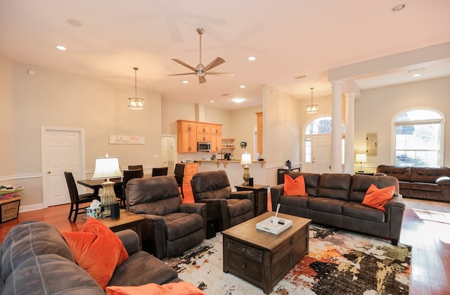 living area featuring light wood-type flooring, decorative columns, a ceiling fan, and recessed lighting