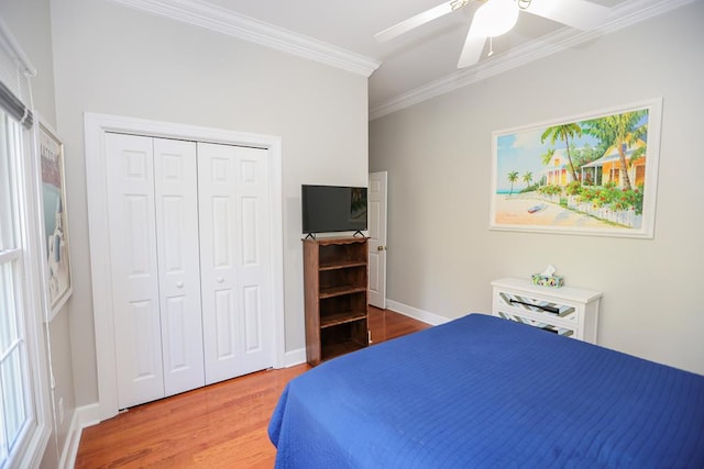 bedroom featuring ornamental molding, wood finished floors, a closet, baseboards, and ceiling fan