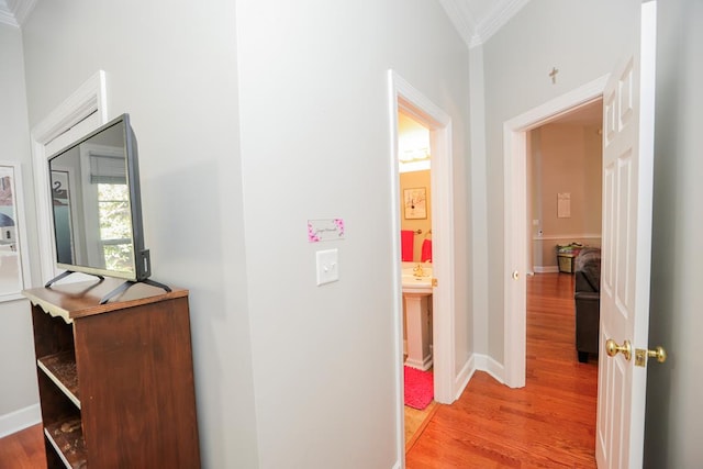 hallway with crown molding, baseboards, and light wood-type flooring