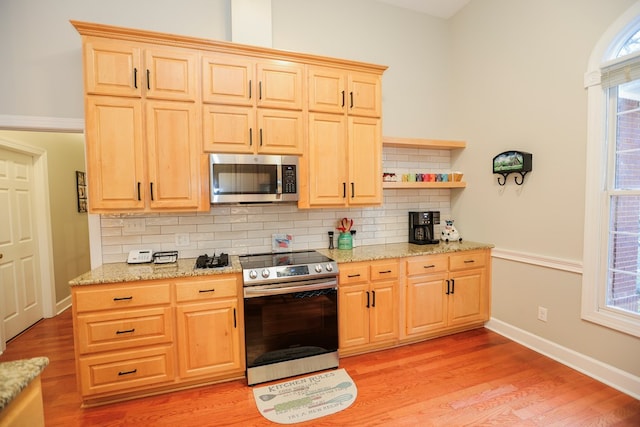 kitchen with light brown cabinets, light wood finished floors, appliances with stainless steel finishes, and backsplash