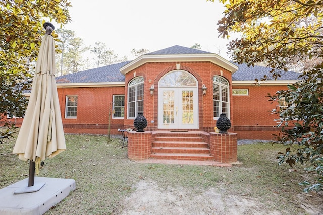 rear view of property with brick siding, french doors, a shingled roof, and entry steps