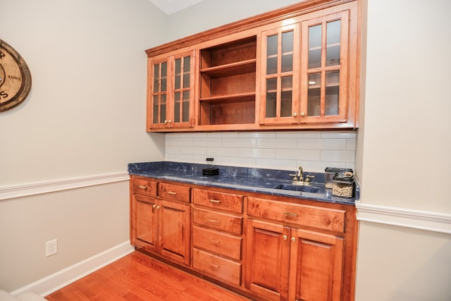 kitchen with decorative backsplash, light wood-style flooring, brown cabinetry, and a sink