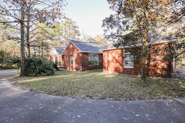 view of front of property with brick siding, a shingled roof, and a front lawn