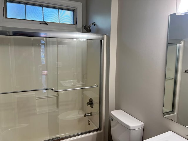 bathroom featuring enclosed tub / shower combo and toilet