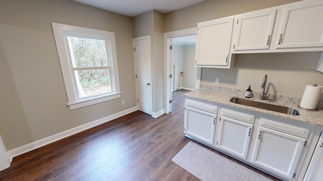 kitchen with white cabinetry, sink, light stone counters, and dark hardwood / wood-style flooring