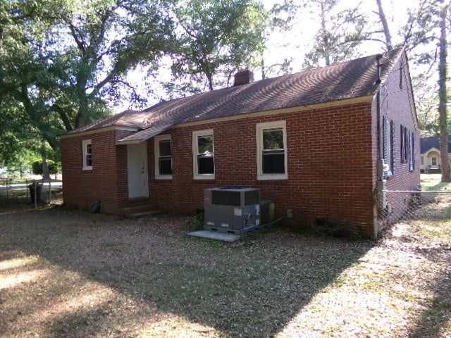 320 Camellia Ct, Camilla, GA 31730 - rear view of property featuring central AC unit, fence, a chimney, and brick siding