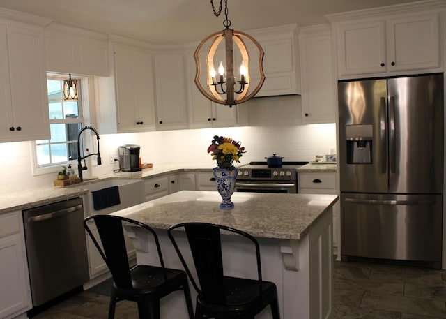 kitchen featuring stainless steel appliances, tasteful backsplash, an inviting chandelier, white cabinets, and a sink