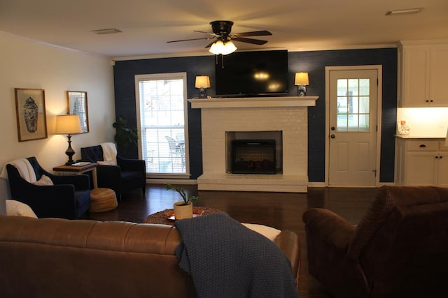 living area featuring a fireplace, wood finished floors, visible vents, and crown molding