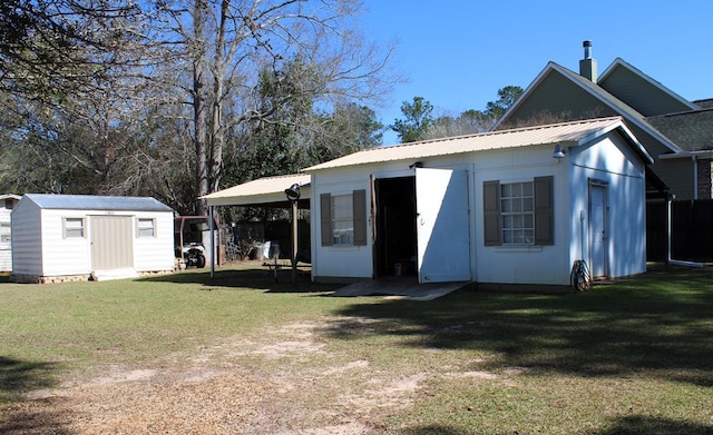 rear view of property with an outbuilding, metal roof, an attached carport, a yard, and driveway