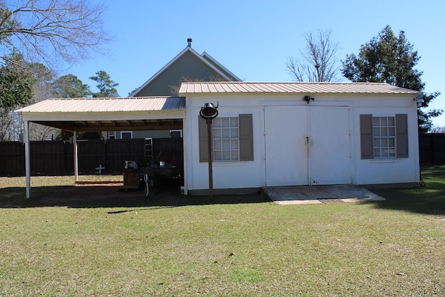 exterior space with a carport, metal roof, a lawn, and fence