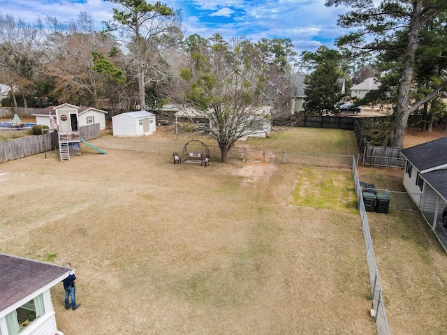 view of yard featuring an outbuilding, a fenced backyard, and a storage unit