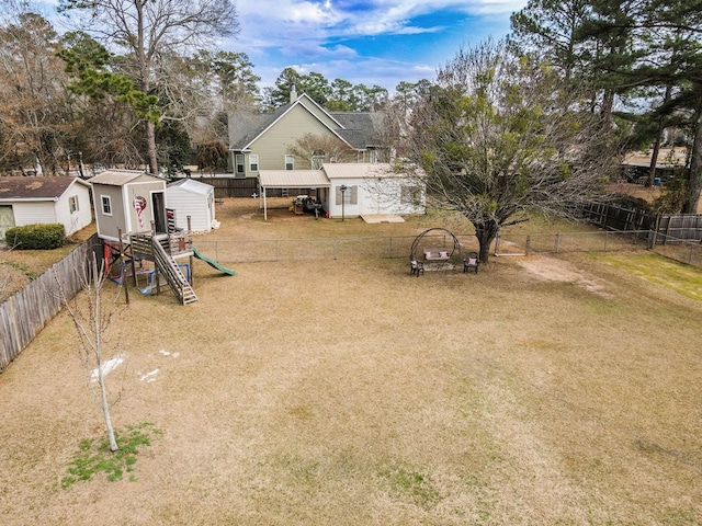 view of yard with a fenced backyard, a storage unit, and an outbuilding