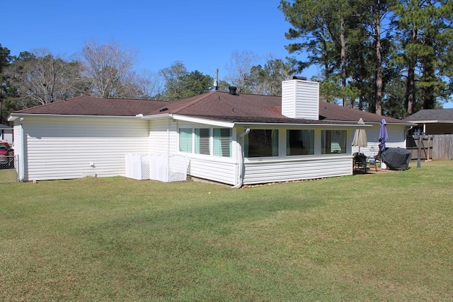 back of property featuring a yard, a chimney, fence, and a sunroom