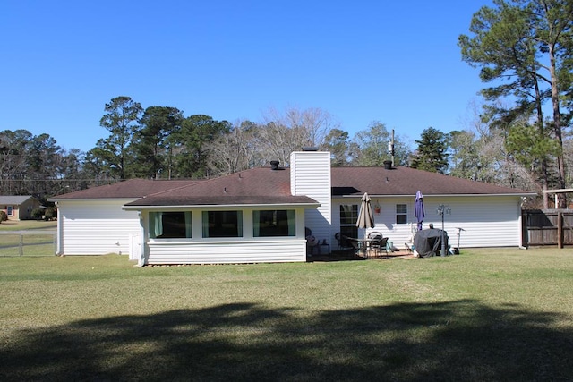 back of property featuring a yard, a chimney, and fence