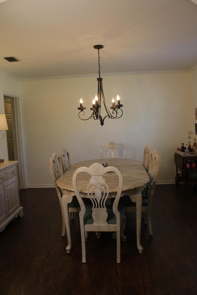 dining area with a chandelier, dark wood-type flooring, visible vents, and crown molding