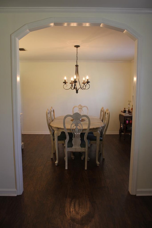 dining area featuring arched walkways, visible vents, dark wood-type flooring, ornamental molding, and baseboards