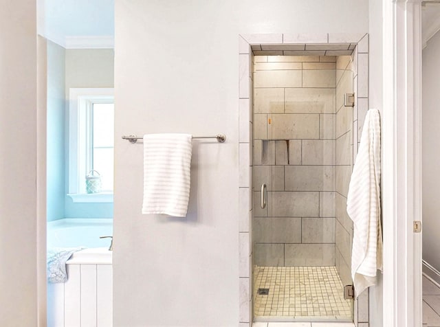 bathroom featuring a stall shower, ornamental molding, and a bath