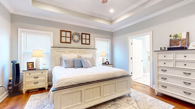 bedroom with crown molding, a tray ceiling, and dark wood-type flooring