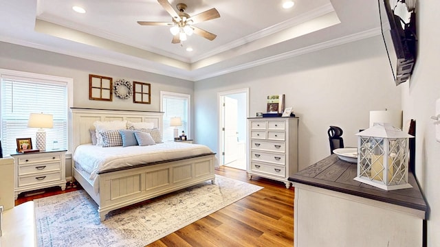 bedroom featuring crown molding, a tray ceiling, wood finished floors, and recessed lighting