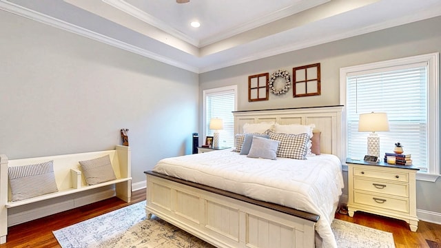 bedroom featuring baseboards, a raised ceiling, ornamental molding, wood finished floors, and recessed lighting