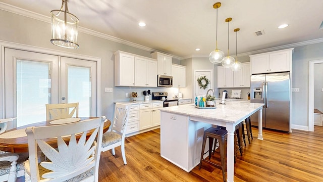 kitchen with stainless steel appliances, a kitchen bar, visible vents, and crown molding