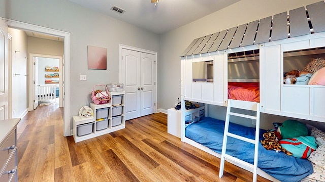 bedroom with a closet, visible vents, baseboards, and wood finished floors