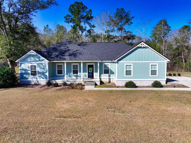 view of front of property featuring roof with shingles, a porch, board and batten siding, and a front yard