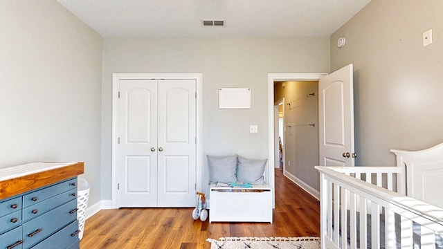 bedroom featuring a closet, wood finished floors, visible vents, and baseboards