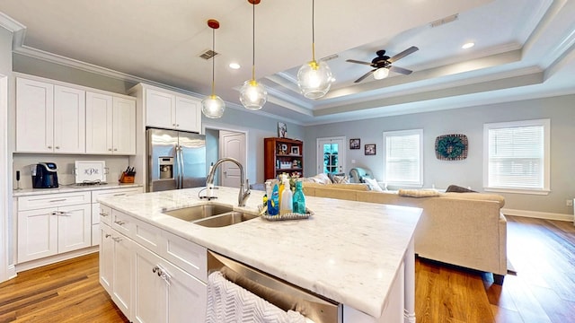 kitchen featuring stainless steel appliances, a sink, visible vents, open floor plan, and a raised ceiling