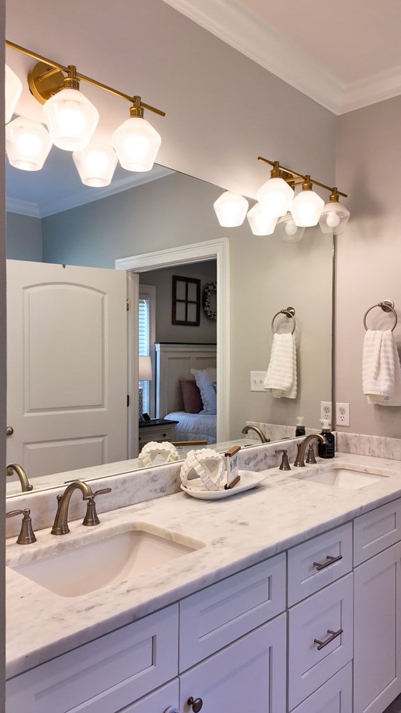 bathroom with double vanity, ornamental molding, ensuite bath, and a sink