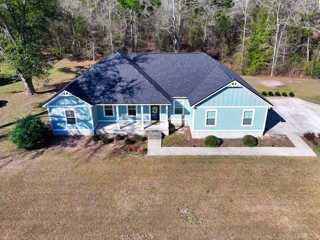 view of front of home featuring driveway, roof with shingles, a front lawn, a porch, and board and batten siding