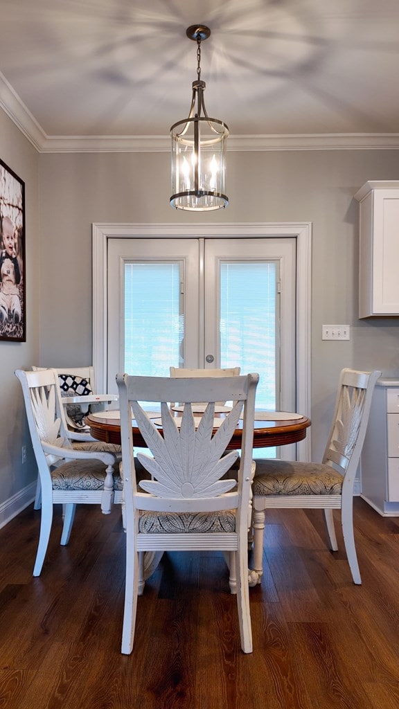 dining area featuring ornamental molding, french doors, a notable chandelier, and wood finished floors