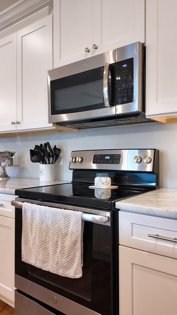 kitchen featuring stainless steel appliances, light countertops, and white cabinetry