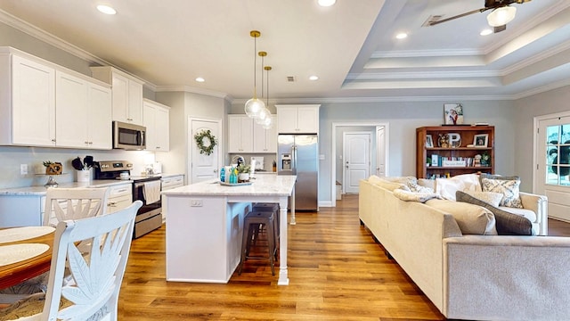 kitchen featuring stainless steel appliances, a breakfast bar, white cabinets, open floor plan, and light wood-style floors