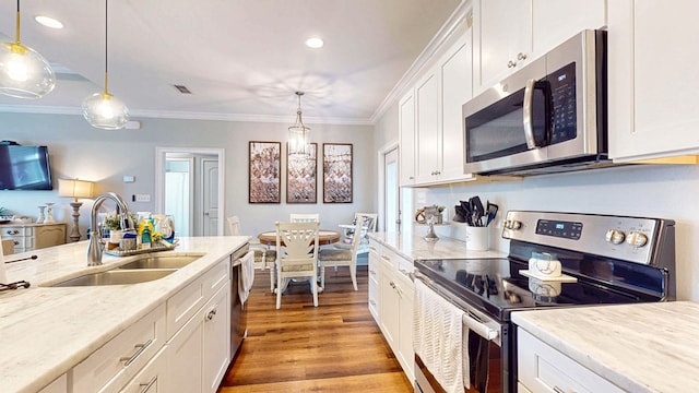 kitchen featuring appliances with stainless steel finishes, white cabinetry, a sink, and ornamental molding