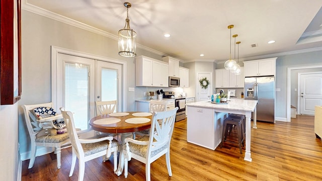 kitchen featuring white cabinets, light wood finished floors, ornamental molding, and stainless steel appliances