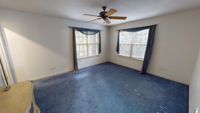 unfurnished room with dark colored carpet and ceiling fan