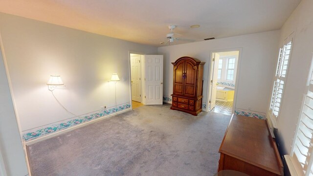 unfurnished bedroom with light colored carpet, ceiling fan, and ensuite bathroom