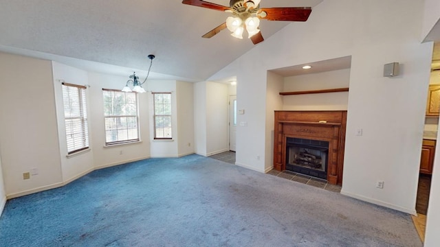 unfurnished living room featuring ceiling fan with notable chandelier, high vaulted ceiling, and carpet