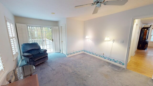 living area with ceiling fan and carpet