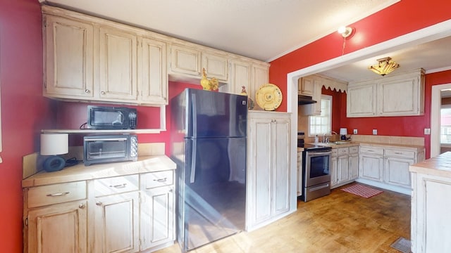 kitchen with light hardwood / wood-style flooring, stainless steel appliances, cream cabinets, ornamental molding, and sink