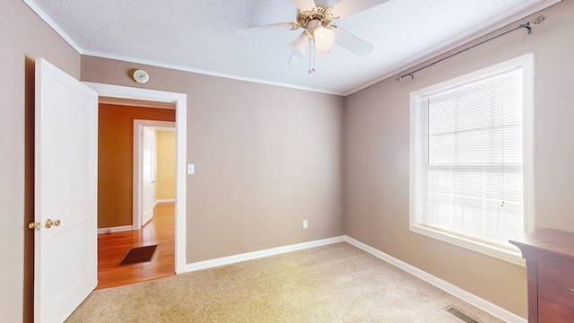 spare room featuring ornamental molding, ceiling fan, a textured ceiling, and light colored carpet