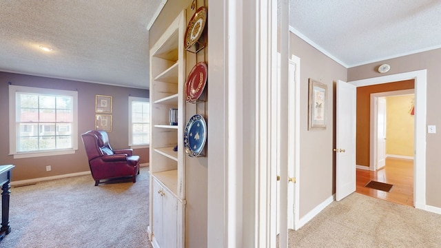 hall featuring ornamental molding, light carpet, and a textured ceiling