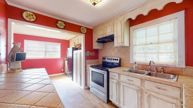 kitchen with tile counters, stainless steel range with electric cooktop, light hardwood / wood-style flooring, sink, and tasteful backsplash