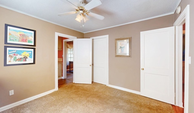 unfurnished bedroom with light colored carpet, a closet, ceiling fan, a textured ceiling, and crown molding