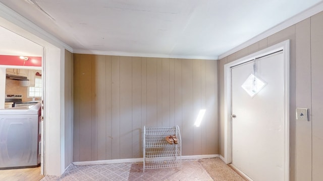 washroom with ornamental molding, washer / dryer, and wooden walls