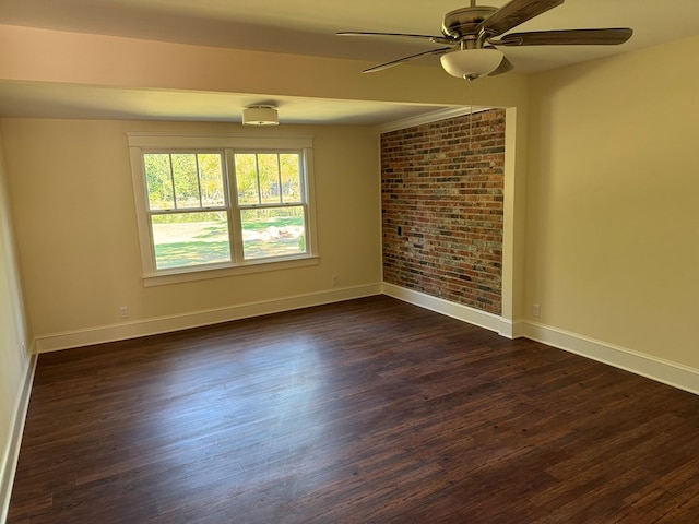 spare room featuring ceiling fan, brick wall, and dark hardwood / wood-style floors