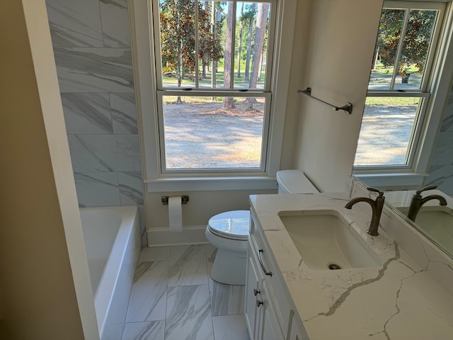 bathroom featuring vanity, a tub, toilet, and a healthy amount of sunlight