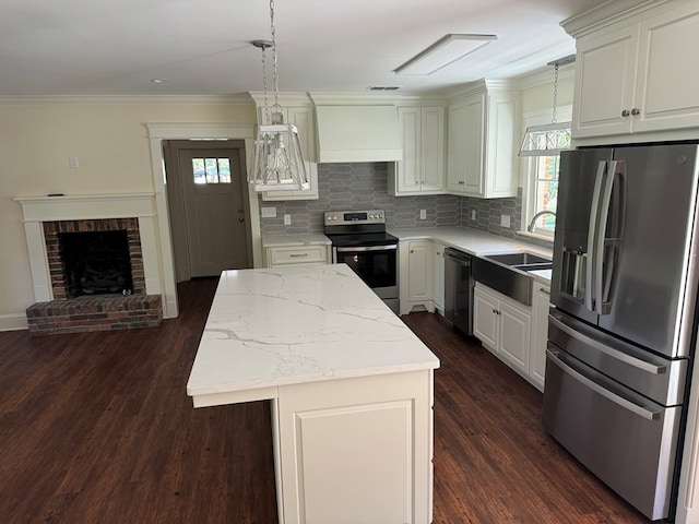 kitchen with premium range hood, sink, decorative light fixtures, appliances with stainless steel finishes, and a kitchen island